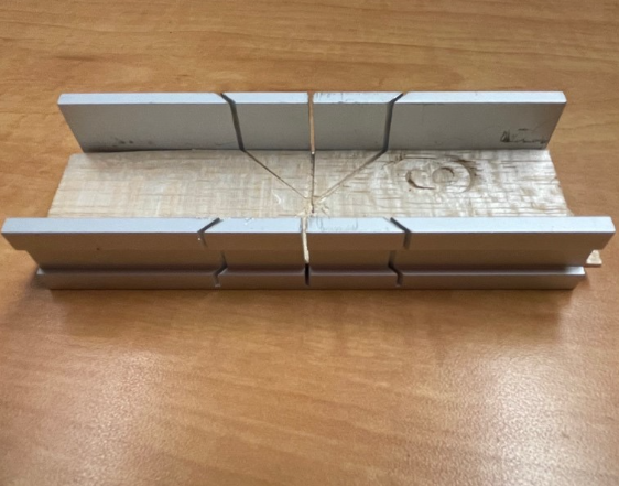 A small miter box that is compatible with a crosscut saw.