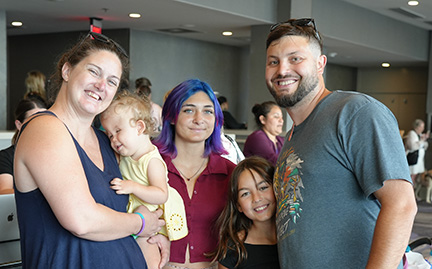 Mom and dad smile with their three daughters at the Braille Book Fair, where they will get some new Braille books to read to their blind infant.
