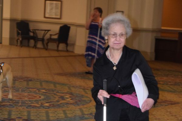 A woman with a white cane walks to a session at the NFB National Convention.