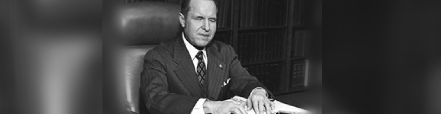 Black and white, Kenneth Jernigan reads Braille at table in a conference room