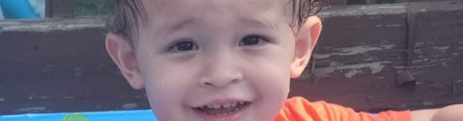 Lucas Matthew wearing an orange T-shirt, wet hair and smiling from ear to ear