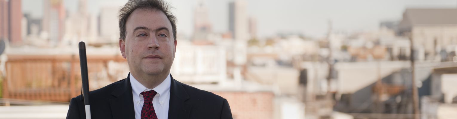 President Riccobono stands outside with view of Baltimore behind him