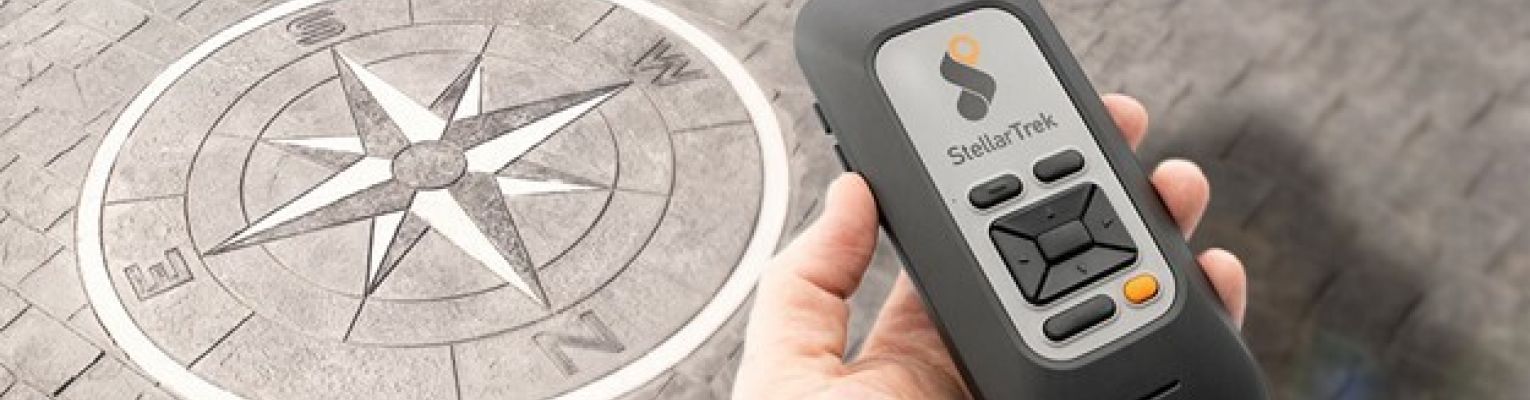 A handheld device with several buttons and no screen appears next to a compass