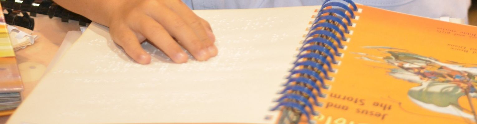 A child's hand on top of a Braille book at the Braille Book Fair at our national convention.