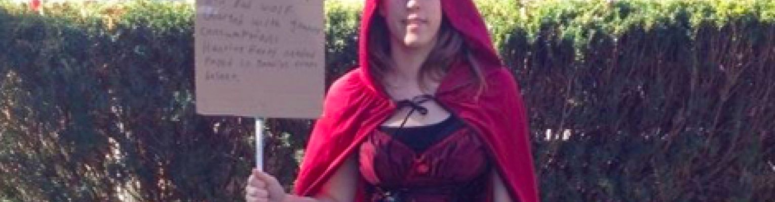 Kelly Coleman stands in a red Halloween costume holding her white cane.