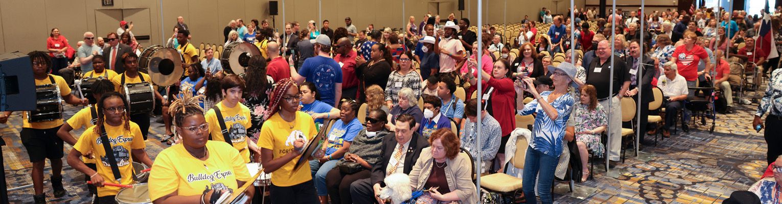 A crowd of NFB members stand and clap along with the opening general session band.