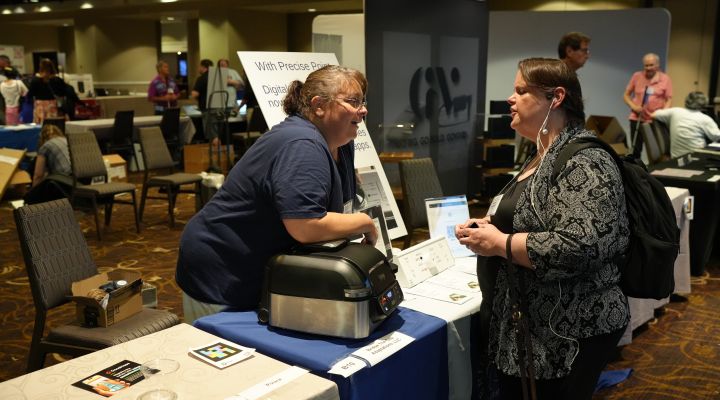 A blind woman speaks with an exhibitor in the exhibit hall