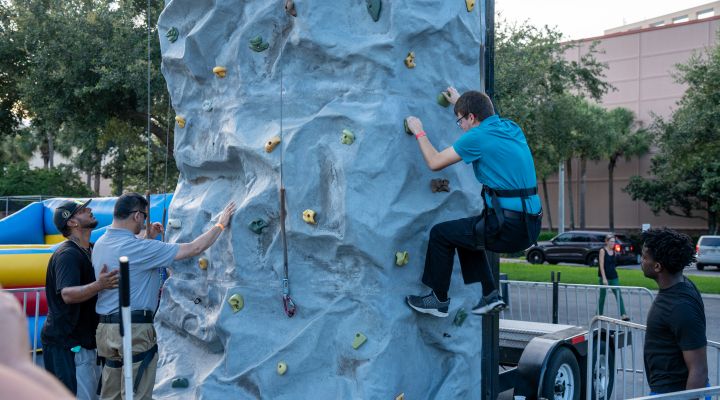 Two blind men climb a rock wall