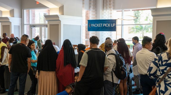 Attendees stand at a packet pickup table to collect their pre-registration materials